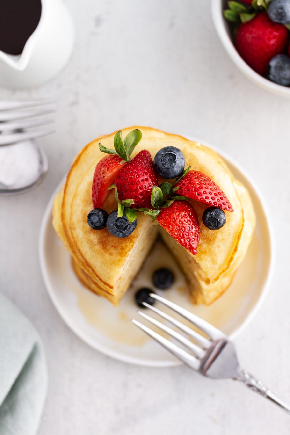 an overhead shot of a stack of coconut flour pancakes on a plate topped with berries