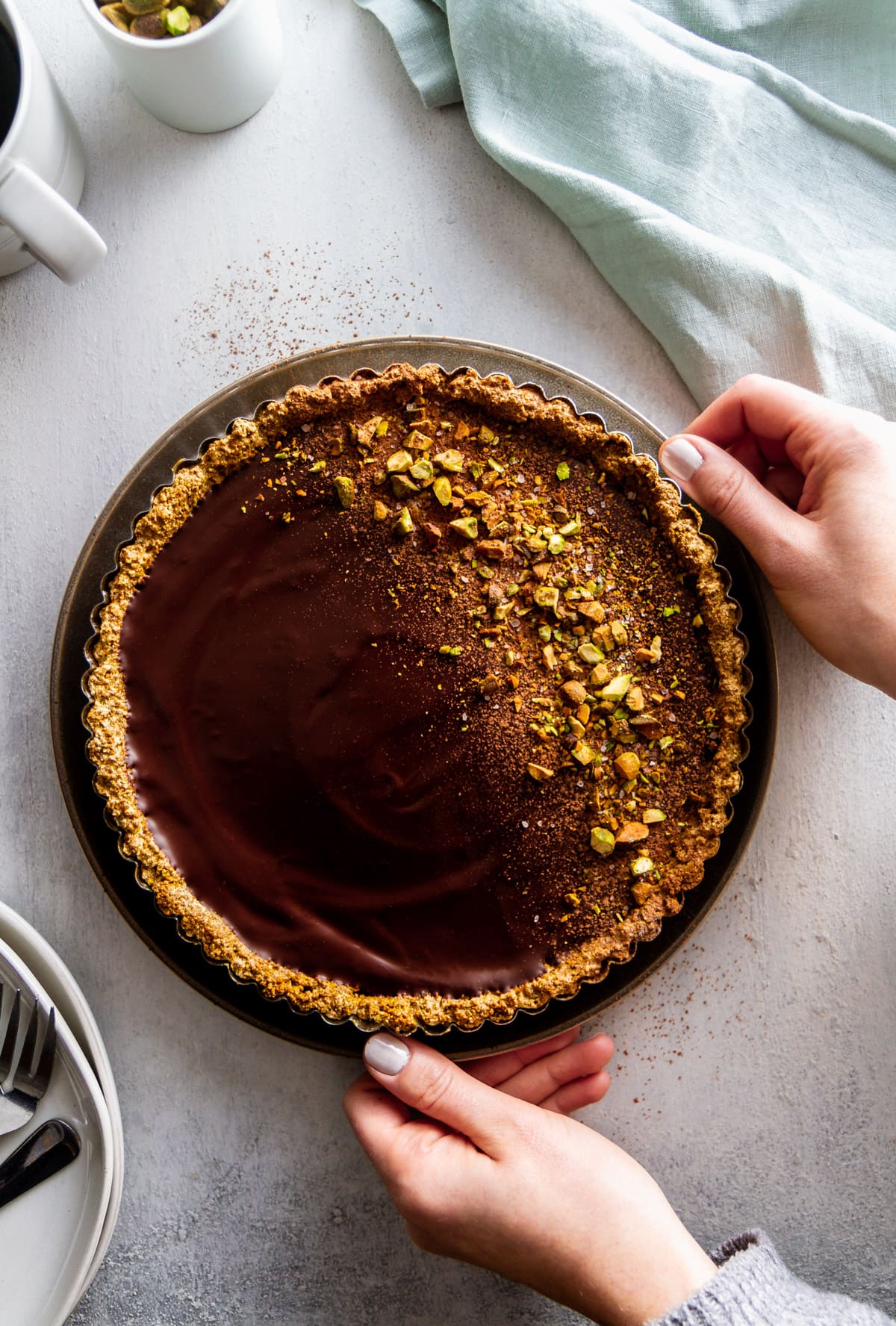 hands placing a chocolate tart on a surface