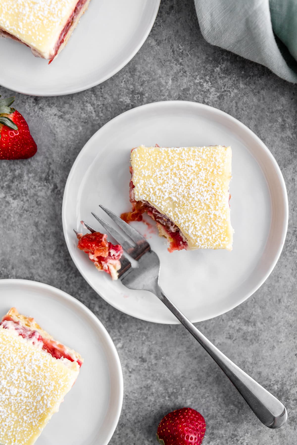 strawberry rhubarb cheesecake bars on plates with a fork