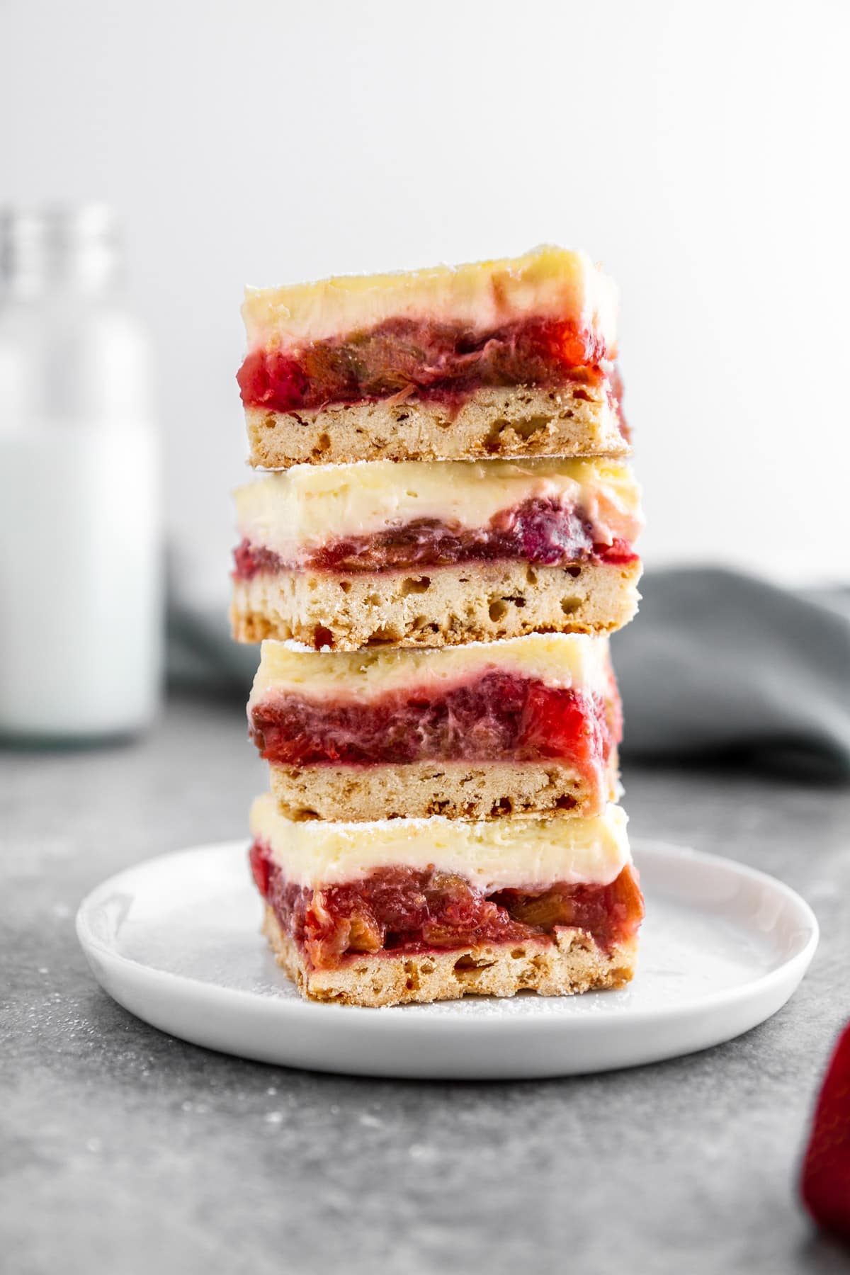 a stack of strawberry rhubarb cheesecake bars on a plate