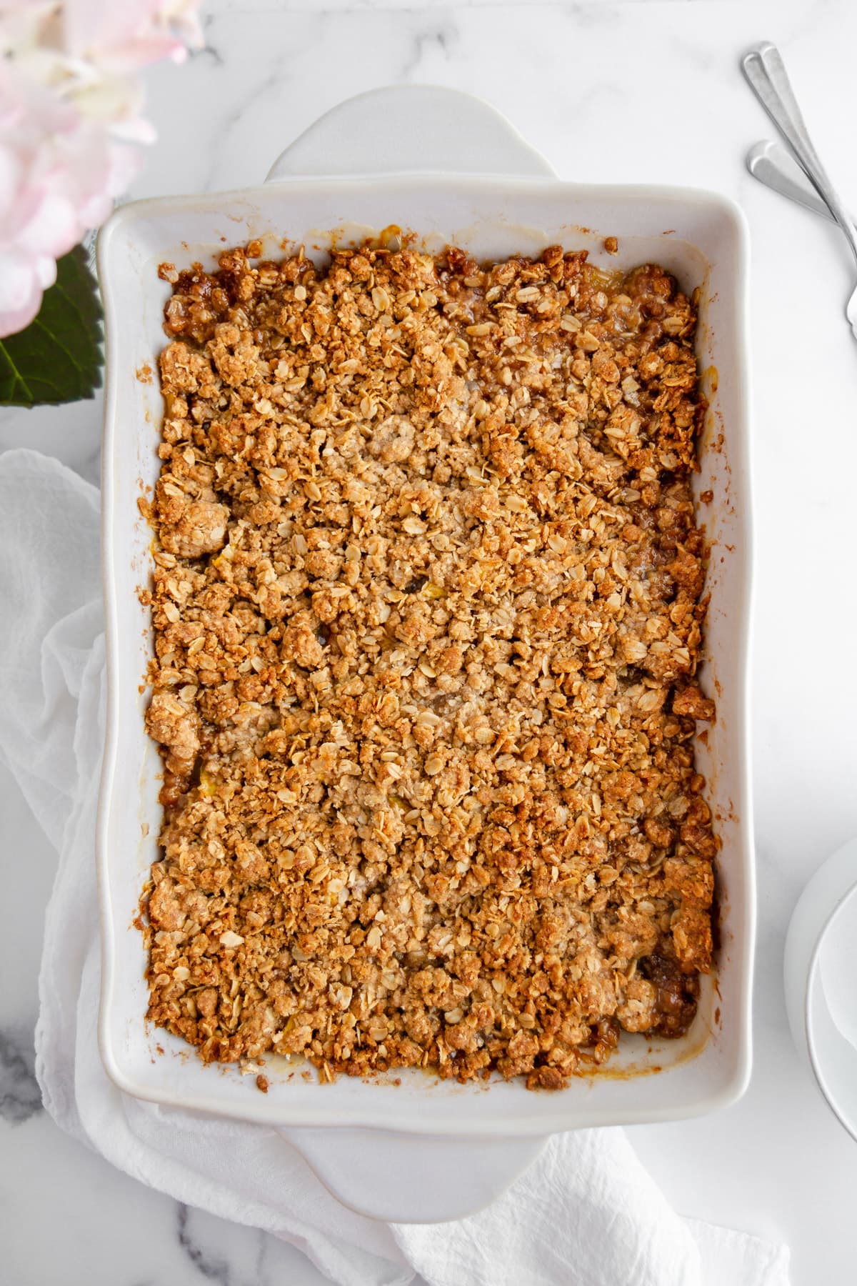 peach crisp with a crunchy oat topping in a baking dish
