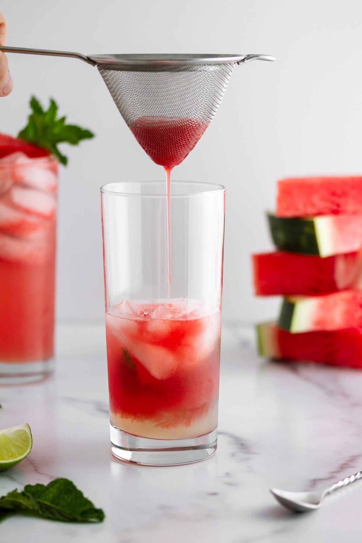 straining watermelon juice into a glass