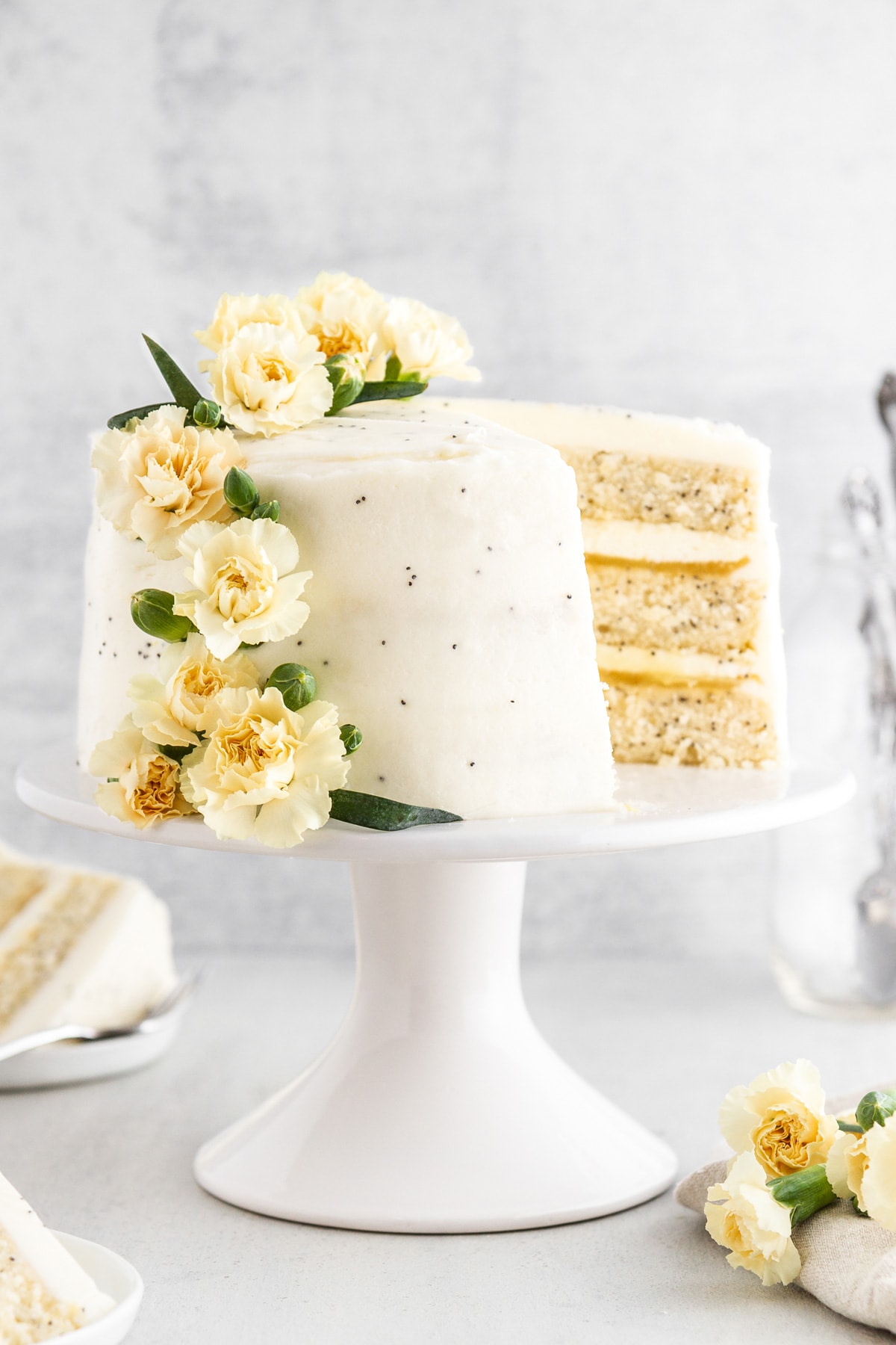 A lemon poppy seed cake on a cake stand with a slice taken out