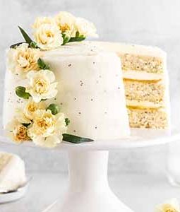 lemon poppy seed cake on a cake stand with a slice taken out