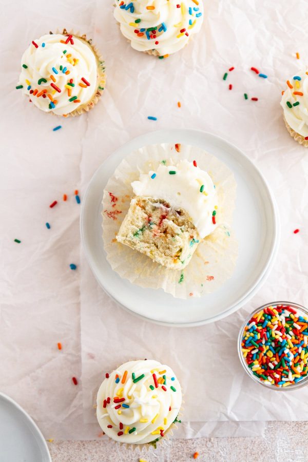 funfetti cupcake cut in half on a plate with other cupcakes on a surface