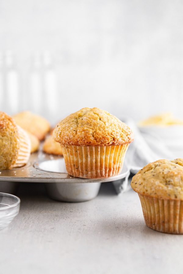 lemon poppy seed muffins on and around a muffin tin