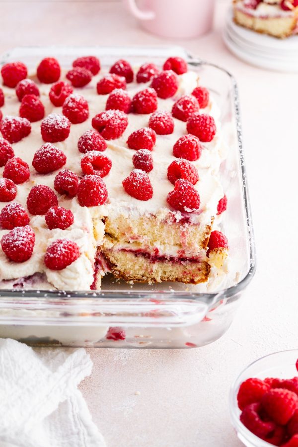 raspberry pound cake tiramisu in a baking dish on a surface with a piece taken out