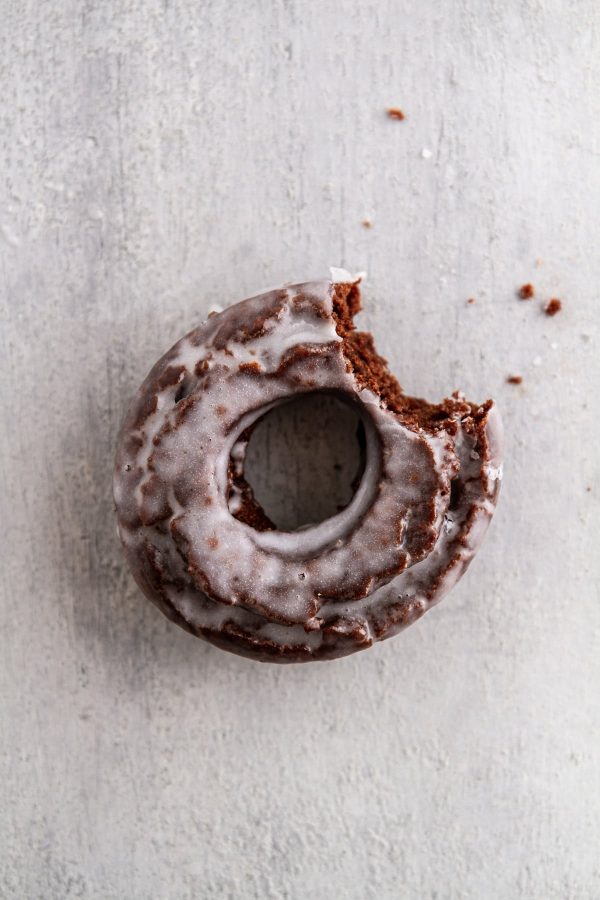 chocolate old-fashioned donut on a surface with a bite taken out