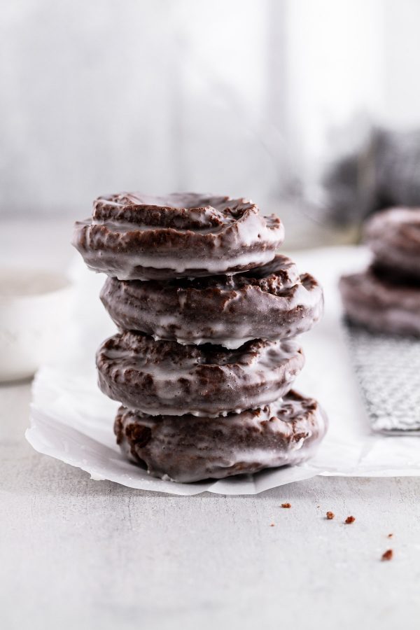stacked chocolate old-fashioned donuts on a sheet of parchment paper