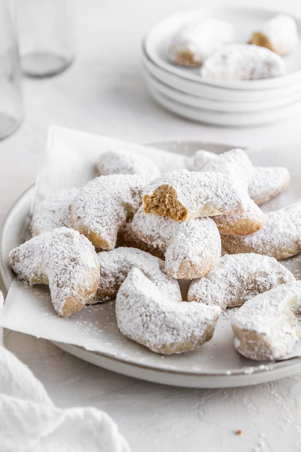 a plate of chai-spiced crescent cookies with a bite taken out of one