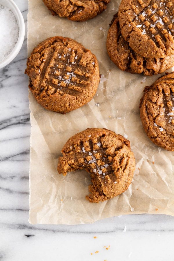 almond butter cookies on a surface with a bite taken out of one cookie